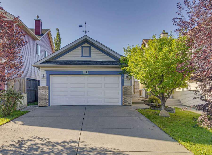 Charming home featuring a classic white garage door with blue trim and house number 13.
