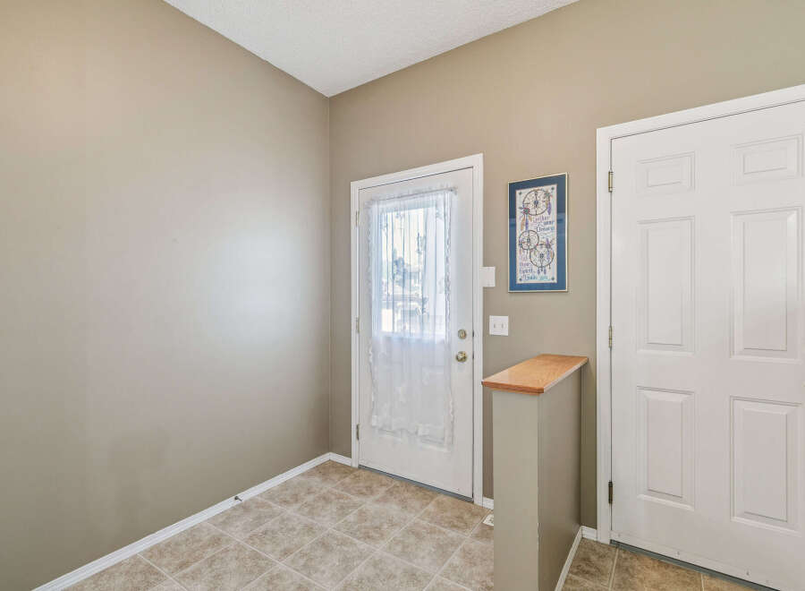 Step into a welcoming entryway featuring a bright front door with a decorative sheer curtain, perfect for letting in natural light.