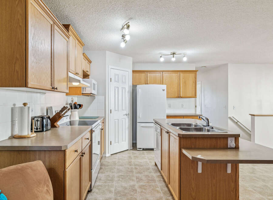 This spacious kitchen features warm oak cabinetry and ample counter space, perfect for meal preparation.