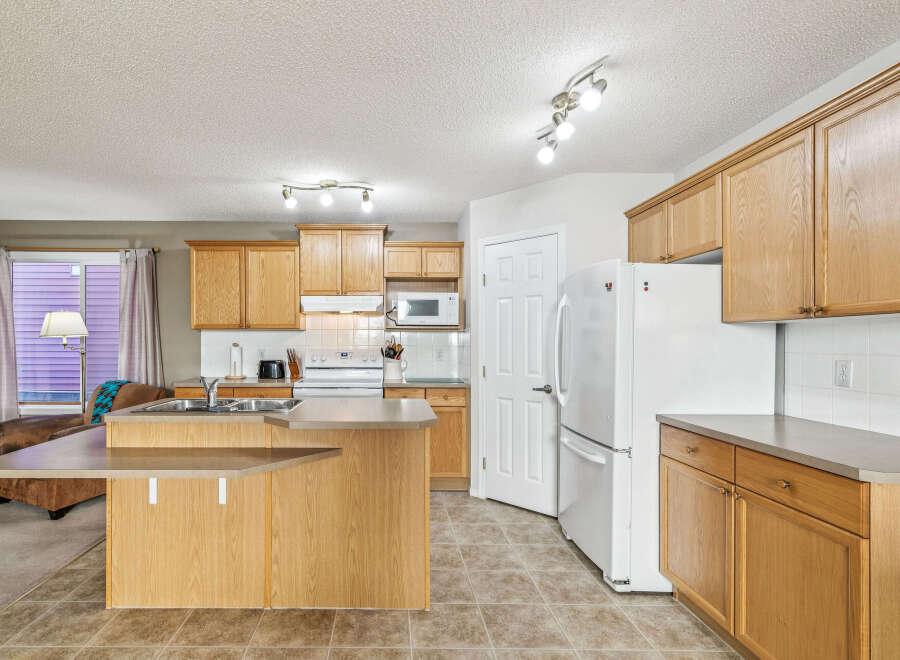 This spacious kitchen features light oak cabinetry and a convenient island with a breakfast bar.