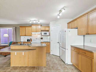 This spacious kitchen features light oak cabinetry and a convenient island with a breakfast bar.