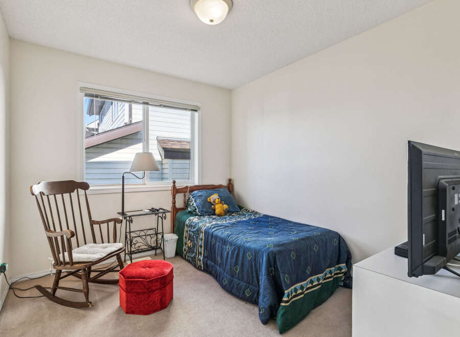 Discover this charming bedroom featuring a comfortable single bed adorned with a playful teddy bear and a cozy blue comforter.