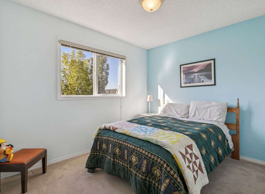 Discover a charming bedroom featuring a comfortable queen-size bed adorned with a beautiful quilt and plush pillows.