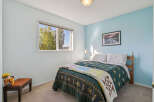 Discover a charming bedroom featuring a comfortable queen-size bed adorned with a beautiful quilt and plush pillows.