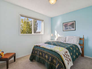 Discover a charming bedroom featuring a comfortable queen-size bed adorned with a beautiful quilt and plush pillows.