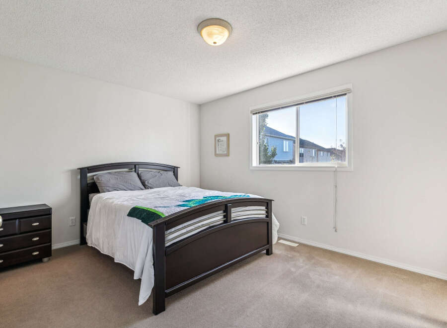 This inviting bedroom features a comfortable queen-size bed with a stylish dark wood frame, complemented by a matching nightstand.
