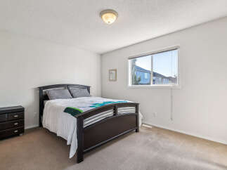 This inviting bedroom features a comfortable queen-size bed with a stylish dark wood frame, complemented by a matching nightstand.