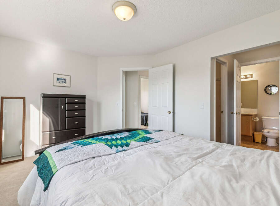 Discover comfort and convenience in this inviting bedroom, featuring a plush bed adorned with a vibrant quilt.
