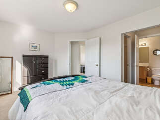 Discover comfort and convenience in this inviting bedroom, featuring a plush bed adorned with a vibrant quilt.