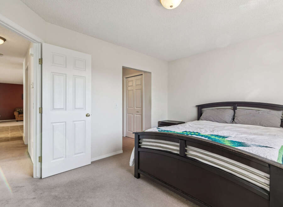 Step into this inviting bedroom featuring a comfortable queen-sized bed adorned with a vibrant, patterned comforter.