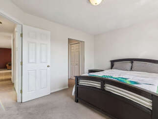 Step into this inviting bedroom featuring a comfortable queen-sized bed adorned with a vibrant, patterned comforter.