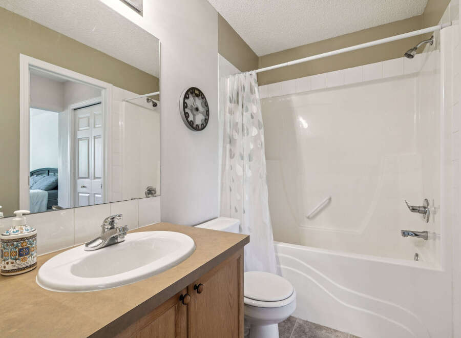 This bright and clean bathroom features a spacious vanity with a large mirror, a modern sink, and a decorative soap dispenser.