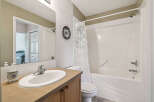 This bright and clean bathroom features a spacious vanity with a large mirror, a modern sink, and a decorative soap dispenser.
