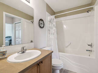 This bright and clean bathroom features a spacious vanity with a large mirror, a modern sink, and a decorative soap dispenser.