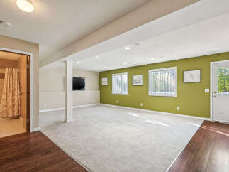 Discover this spacious finished basement featuring a large open living area with plush carpeting and a vibrant accent wall.