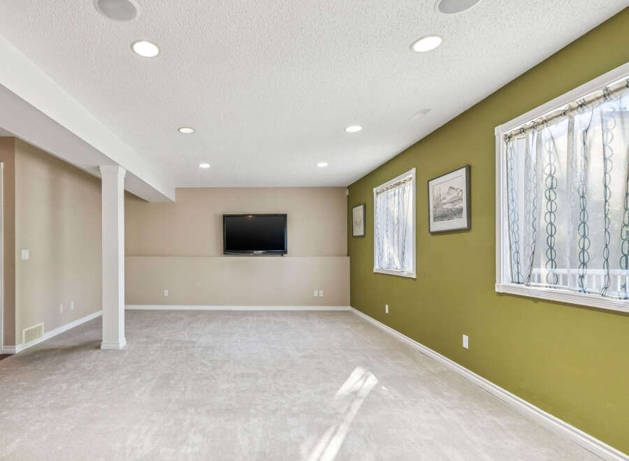 This spacious basement features a large open area perfect for entertainment, complete with a mounted flat-screen TV.