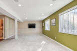 This spacious basement features a large open area perfect for entertainment, complete with a mounted flat-screen TV.