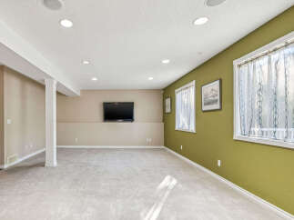This spacious basement features a large open area perfect for entertainment, complete with a mounted flat-screen TV.