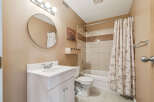 This bathroom features a white vanity with a double-door cabinet, a round mirror, and a vanity light fixture.