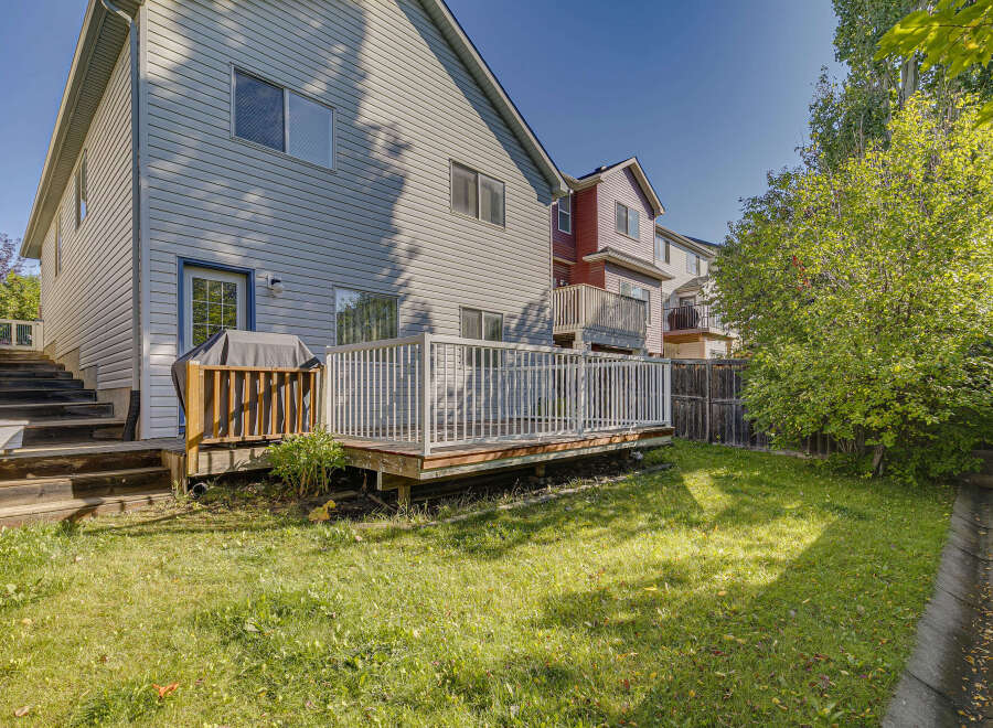 Enjoy outdoor living with this spacious backyard featuring a large wooden deck and a covered grill area, perfect for entertaining.