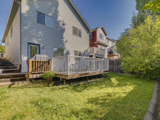 Enjoy outdoor living with this spacious backyard featuring a large wooden deck and a covered grill area, perfect for entertaining.