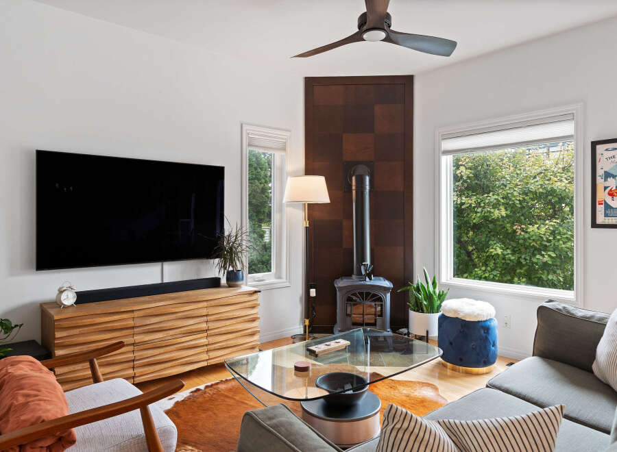 Experience modern living in this stylish living room, featuring a sleek entertainment center and a cozy wood-burning stove.