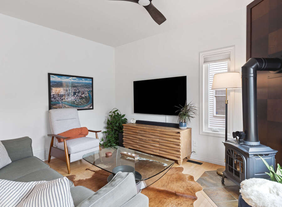 Experience modern living in this stylish living room, featuring a sleek entertainment center and a cozy armchair perfect for relaxation.