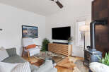 Experience modern living in this stylish living room, featuring a sleek entertainment center and a cozy armchair perfect for relaxation.