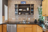 This kitchen boasts a stylish backsplash with a mix of subway and mosaic tiles, complemented by a sleek stainless steel sink and faucet.
