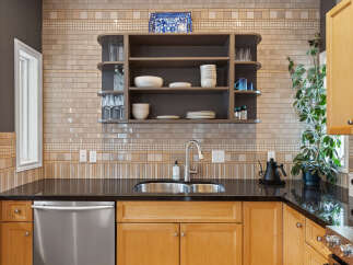 This kitchen boasts a stylish backsplash with a mix of subway and mosaic tiles, complemented by a sleek stainless steel sink and faucet.