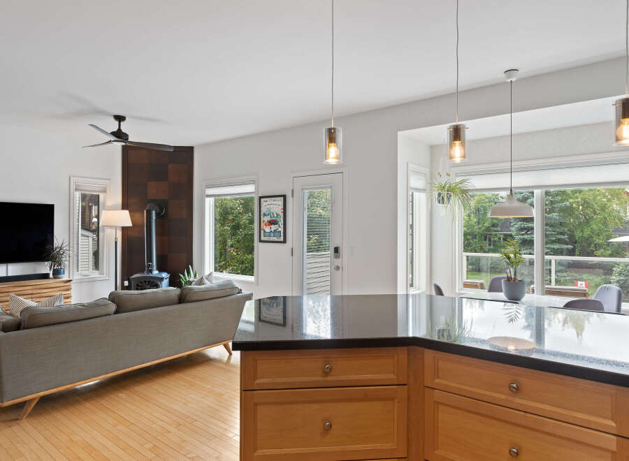 Experience modern living in this open-concept home featuring a sleek kitchen island with granite countertops and warm wood cabinetry.