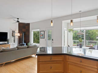 Experience modern living in this open-concept home featuring a sleek kitchen island with granite countertops and warm wood cabinetry.