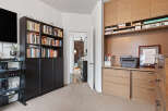 This home office space features a large built-in wooden desk with ample storage, including drawers and shelving.
