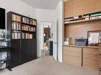 This home office space features a large built-in wooden desk with ample storage, including drawers and shelving.