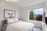 This bright bedroom features a comfortable bed with a stylish black and white Highland cow print above it.