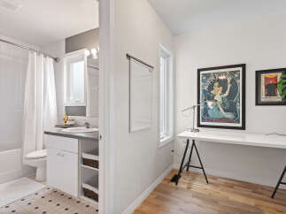 Discover a versatile space with a modern bathroom featuring a bathtub, toilet, and vanity, complemented by a bright workspace.