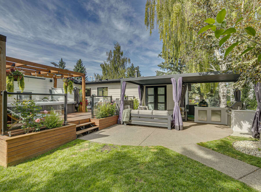 Experience ultimate outdoor living with this stunning backyard oasis, featuring a luxurious hot tub on a spacious wooden deck.