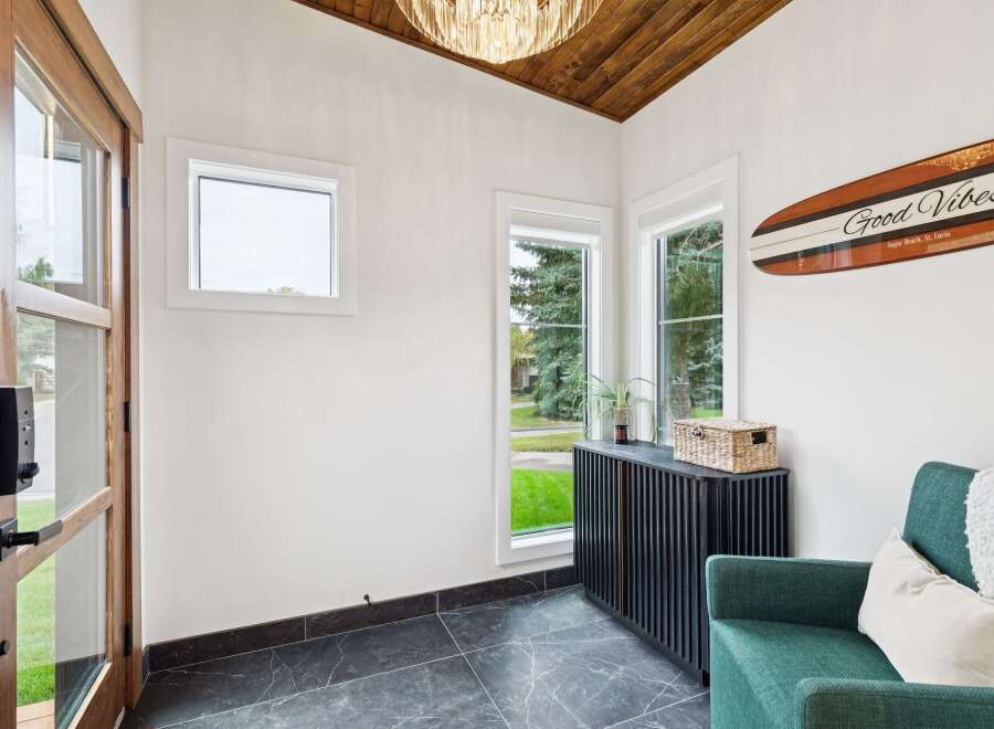 Step into this inviting entryway featuring a stunning wood-paneled vaulted ceiling and a modern crystal chandelier.