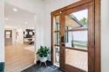 Step into a beautifully designed entryway featuring a stunning wooden double door with glass panels, offering a glimpse of the outdoor deck.