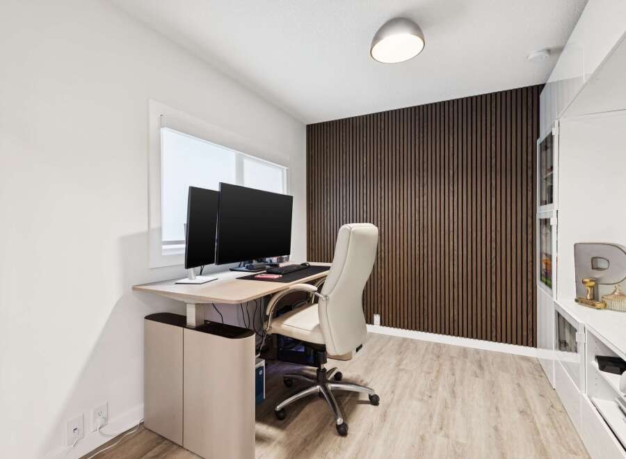 This modern home office features a sleek, height-adjustable desk with dual monitors, perfect for productivity.
