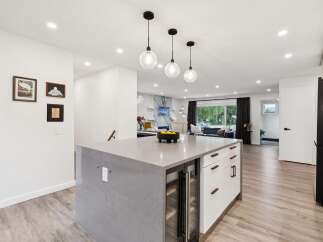 Experience modern living in this stunning open-concept kitchen, featuring a sleek island with a built-in wine fridge and ample counter space.