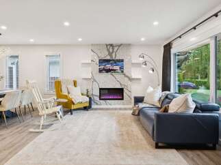 Experience modern living in this spacious open-concept living area, featuring a stunning granite-clad fireplace as the centerpiece.