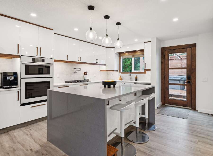 Experience modern luxury in this stunning kitchen featuring sleek white cabinetry with warm wood accents and a spacious grey quartz island perfect for entertaining.