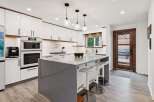 Experience modern luxury in this stunning kitchen featuring sleek white cabinetry with warm wood accents and a spacious grey quartz island perfect for entertaining.