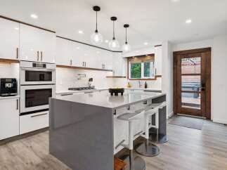 Experience modern luxury in this stunning kitchen featuring sleek white cabinetry with warm wood accents and a spacious grey quartz island perfect for entertaining.