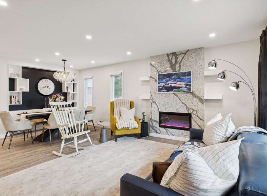 Experience modern living in this spacious open-concept home, featuring a sleek dining area with a statement chandelier and a cozy living room centered around a stunning stone fireplace.