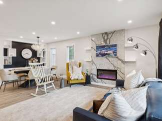 Experience modern living in this spacious open-concept home, featuring a sleek dining area with a statement chandelier and a cozy living room centered around a stunning stone fireplace.