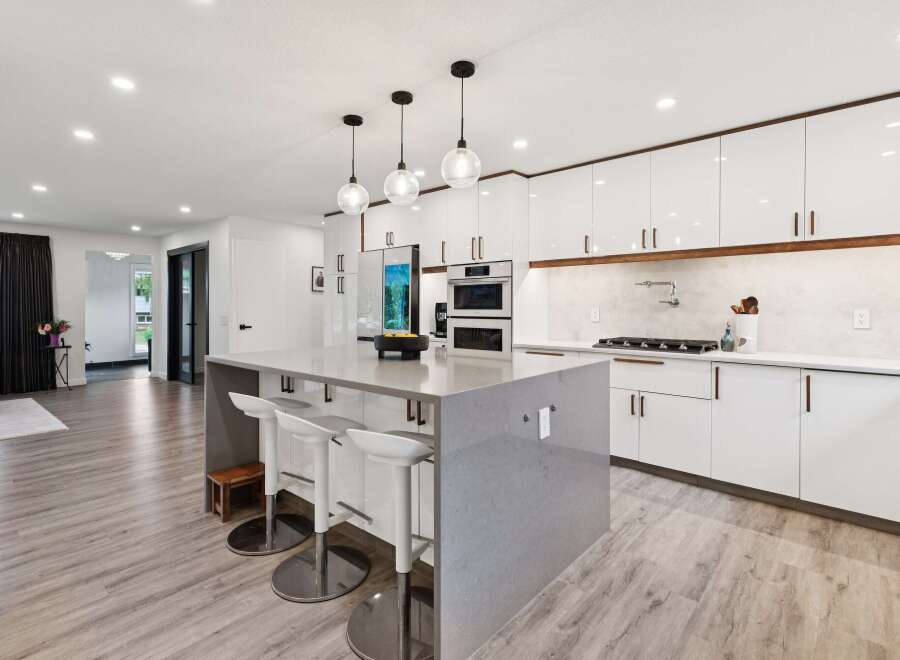 Experience modern luxury in this stunning kitchen, featuring sleek white cabinetry with warm wood accents and a spacious quartz island perfect for entertaining.