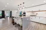 Experience modern luxury in this stunning kitchen, featuring sleek white cabinetry with warm wood accents and a spacious quartz island perfect for entertaining.