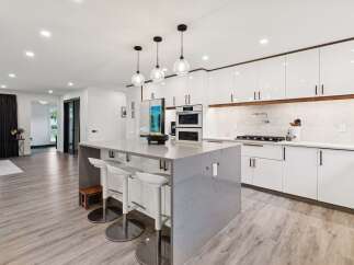 Experience modern luxury in this stunning kitchen, featuring sleek white cabinetry with warm wood accents and a spacious quartz island perfect for entertaining.